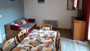 Pieni, viihtyisä huone, jossa on sänky, työpöytä, tuoli, patteri ja televisio.