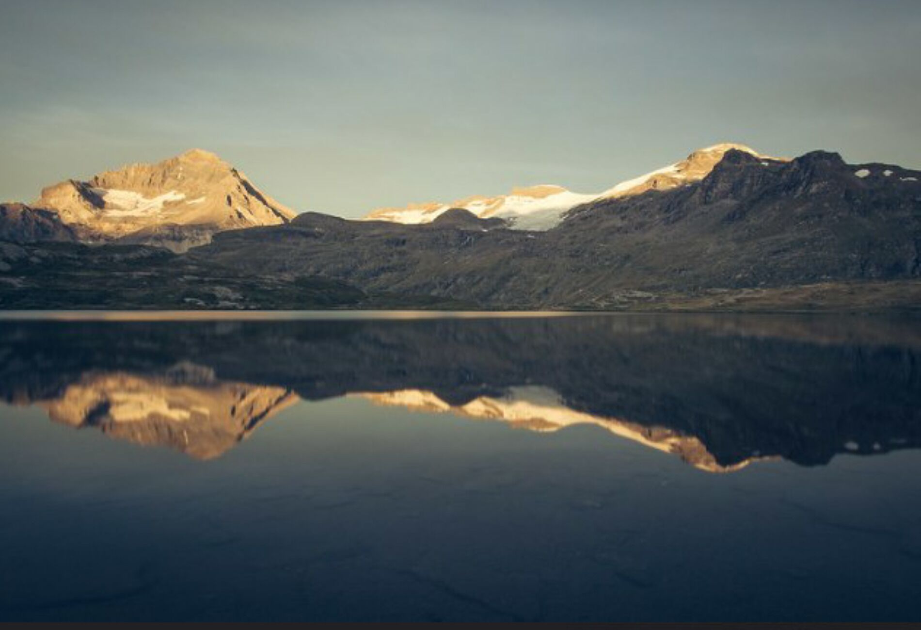 Un paisaje montañoso con un lago tranquilo que refleja las montañas.