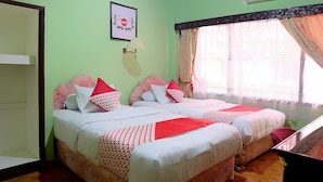 A room with two beds, a wall-mounted air conditioner, a framed picture, and a window with curtains.