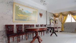 A dining area with a marble wall, a large landscape painting, and a table with chairs.