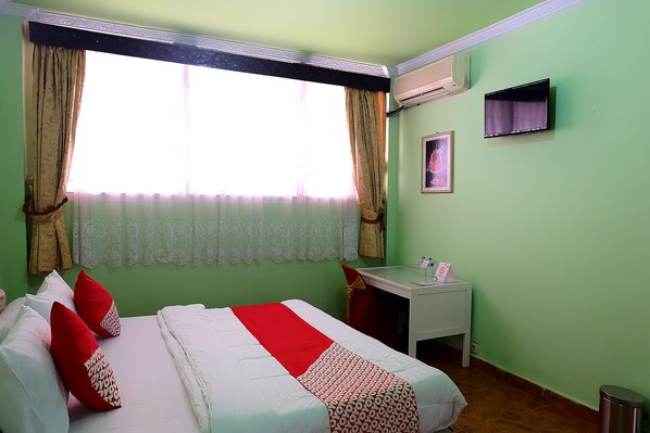 Una habitación de hotel con cama, escritorio y ventana con cortinas.