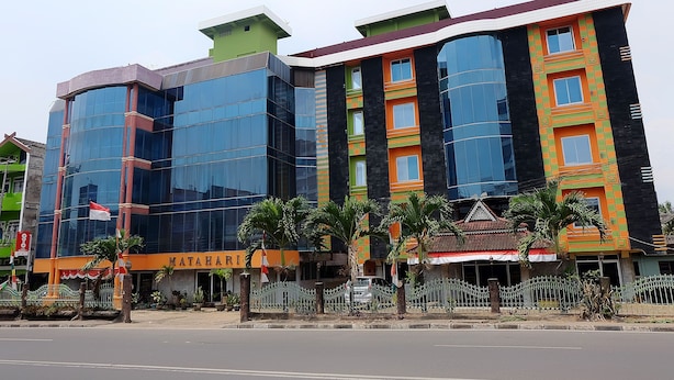 A multi-story building with a modern glass facade, a sign reading "MATAHA," and a gated entrance with palm trees.
