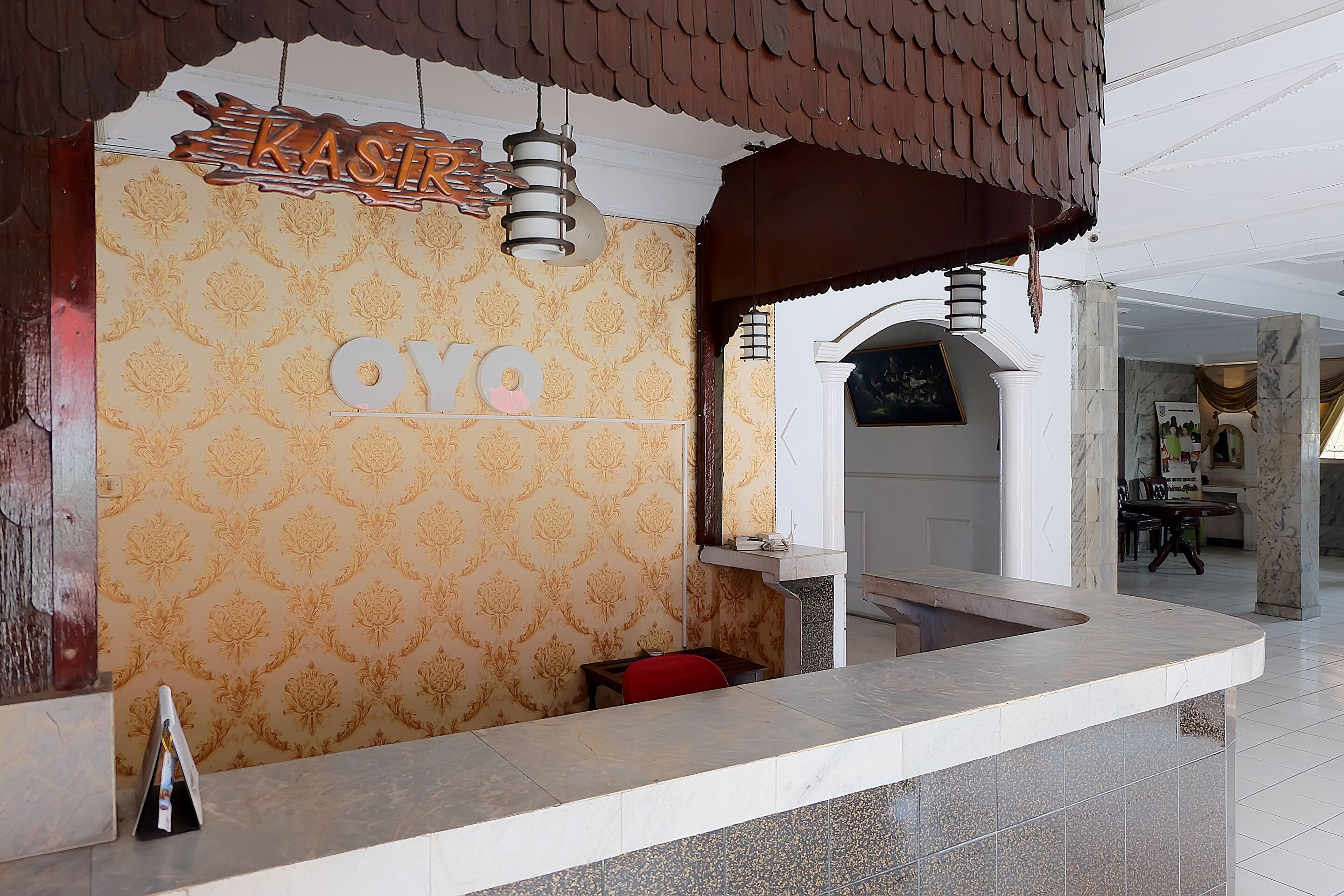 Un área de recepción con una pared estampada, un letrero de madera sobre el mostrador y una encimera de mármol.