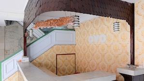 A reception area with a marble counter, a sign reading "RECEPTIONIST," and a patterned wall with the letters "OYO" visible.