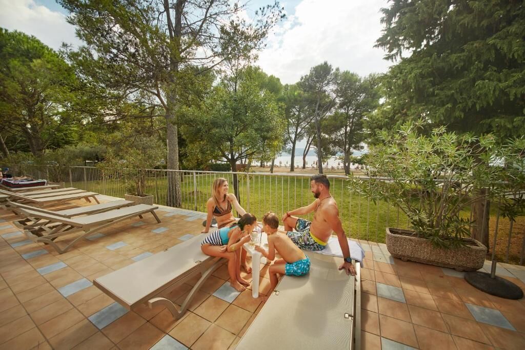 A patio area with lounge chairs, a dining table, and a view of the sea.