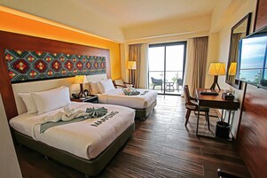 Habitación de hotel con dos camas, un escritorio, una silla y un balcón con vistas.