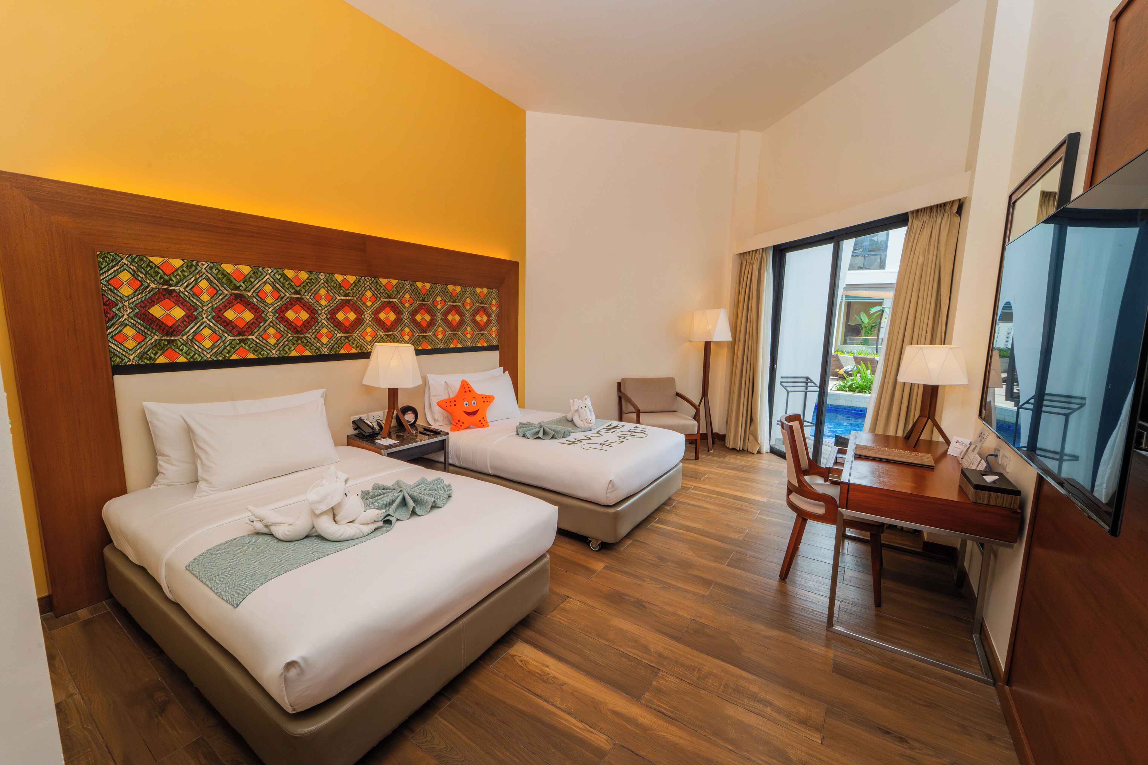 A hotel room with two beds, a desk, and a chair.
