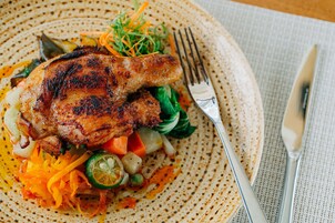 Un plato de comida con un muslo de pollo a la parrilla, verduras y una ensalada.