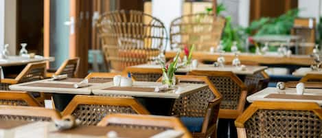 Un restaurante con mesas y sillas de madera, algunas con plantas encima.