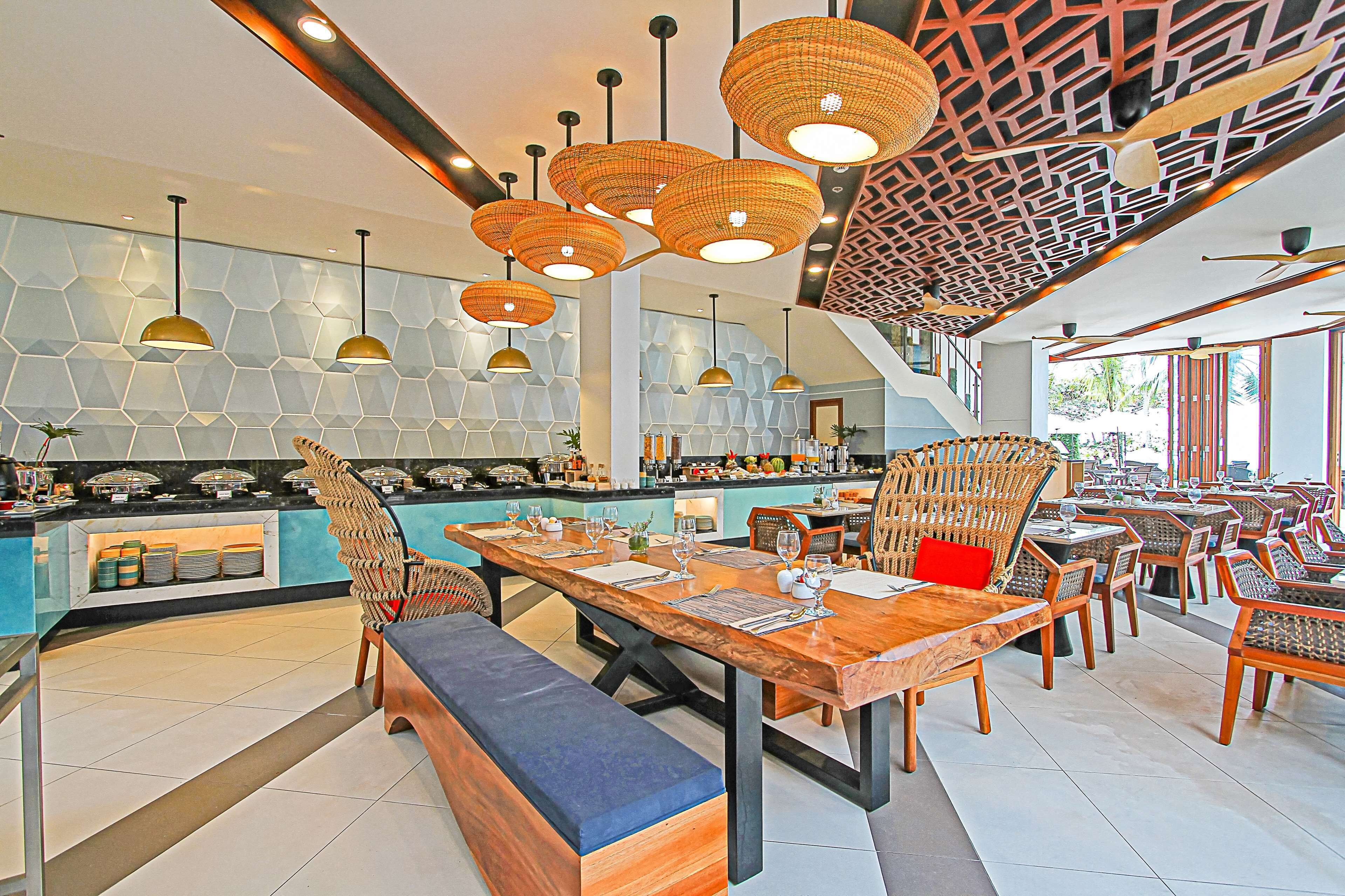 Un restaurant moderne avec un long comptoir, des chaises en osier et des tables en bois.