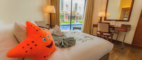 A hotel room with a bed, a desk, a chair, a large mirror, and a view of a swimming pool.