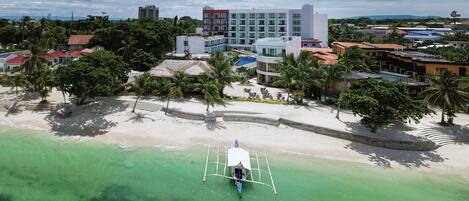 A coastal resort with a beach, palm trees, and a clear view of the ocean.
