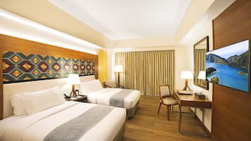 A hotel room with two beds, a desk, a chair, a TV, and a view of a mountainous landscape.