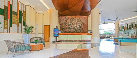 A spacious lobby with a curved floor, a reception desk, and a large wall with a decorative panel.
