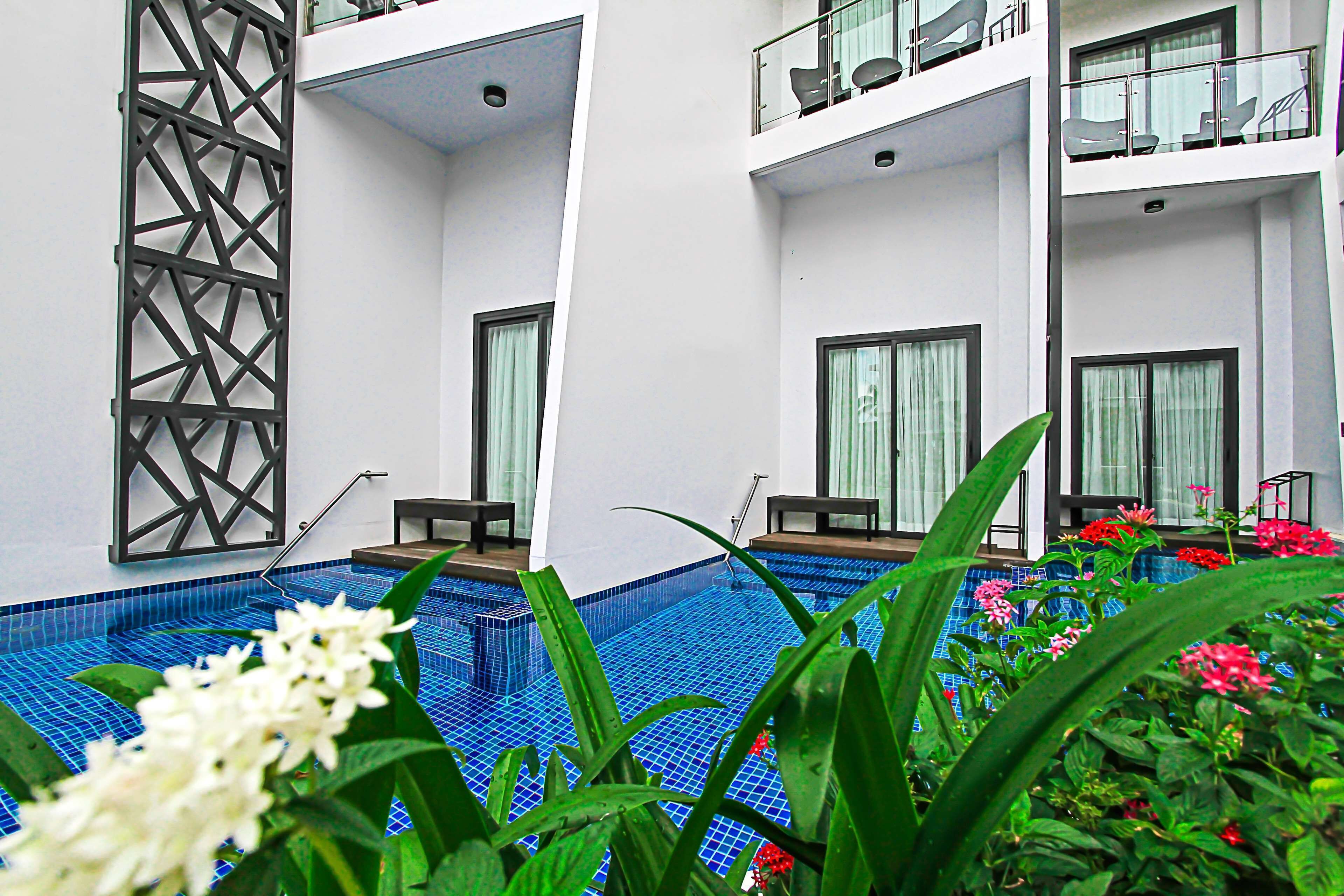 A modern hotel with a swimming pool, balconies with seating, and a decorative metal partition.