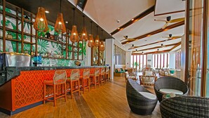 A bar area with a wooden floor, orange seating, and a green leafy wall design.