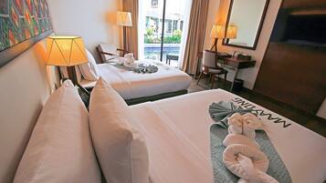 Habitación de hotel con dos camas, un escritorio, una silla y vista a una piscina y un edificio a través de la ventana.