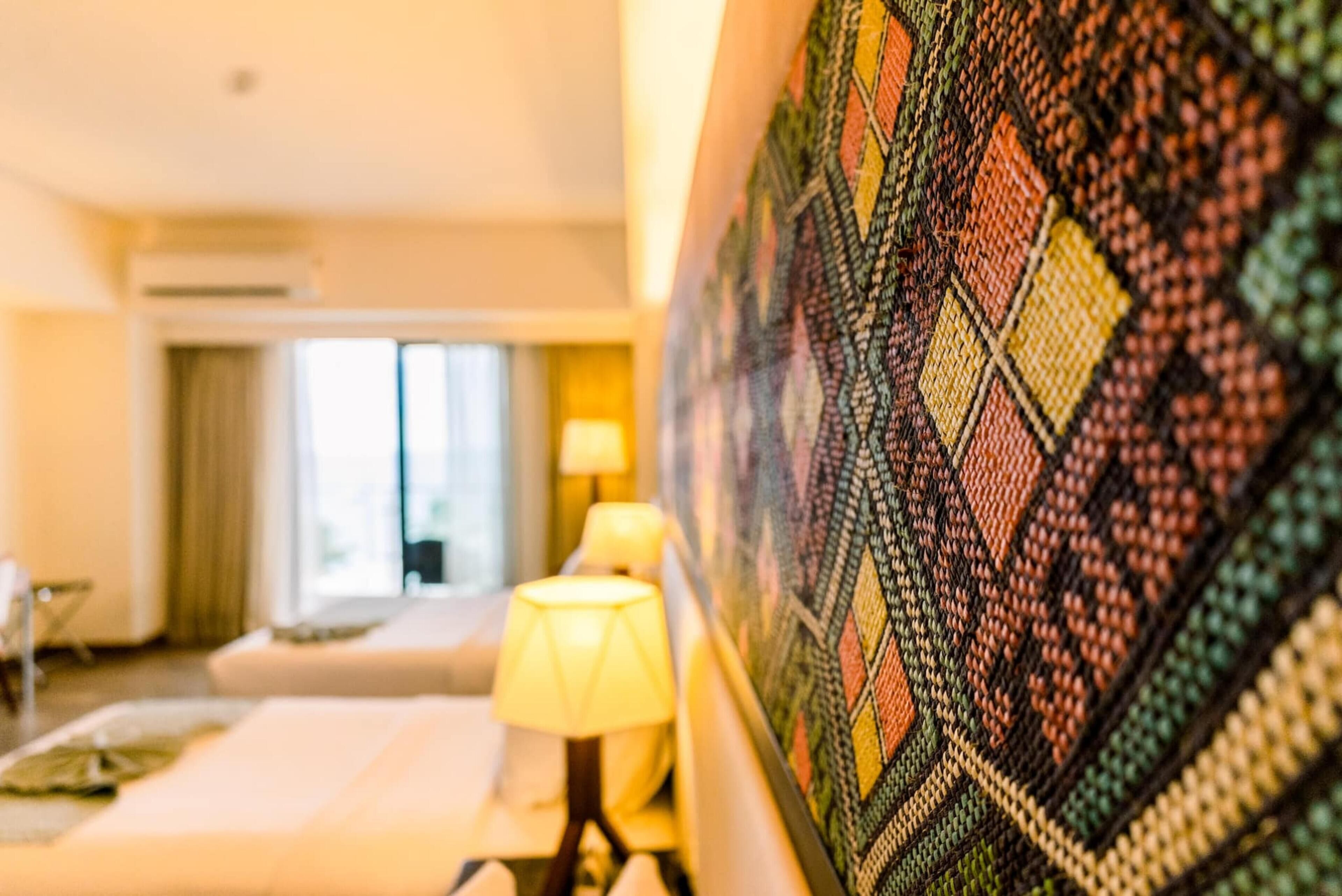 Une chambre d’hôtel avec un lit, une lampe de chevet et une grande décoration murale à motifs.