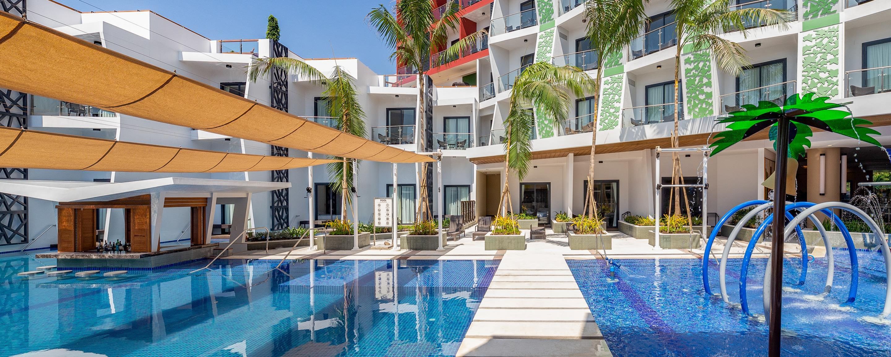 A modern hotel with a pool area, including a sign indicating GSTC certification.