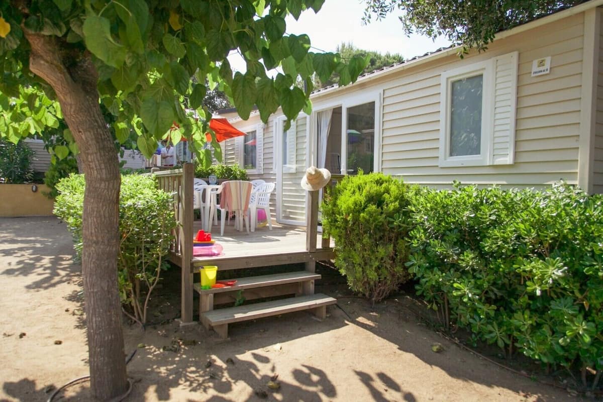 Een stacaravan met een terras, tuinmeubilair en een kleine tuin.