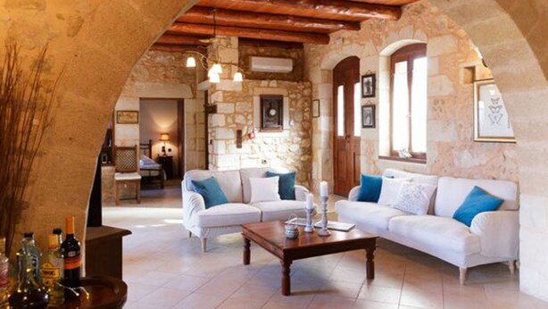A cozy living room with stone walls, a wooden ceiling, and a white sofa with blue cushions. - Villa Patriko Lux villa with pool next to Balos (Kissamos)