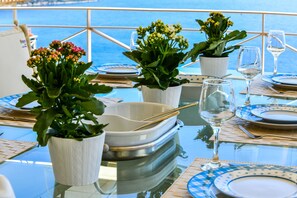 Une table dressée pour le repas, avec des assiettes blanches et bleues, un verre transparent et des plantes en pot.