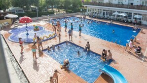 A swimming pool area with multiple pools, water slides, and lounge chairs.