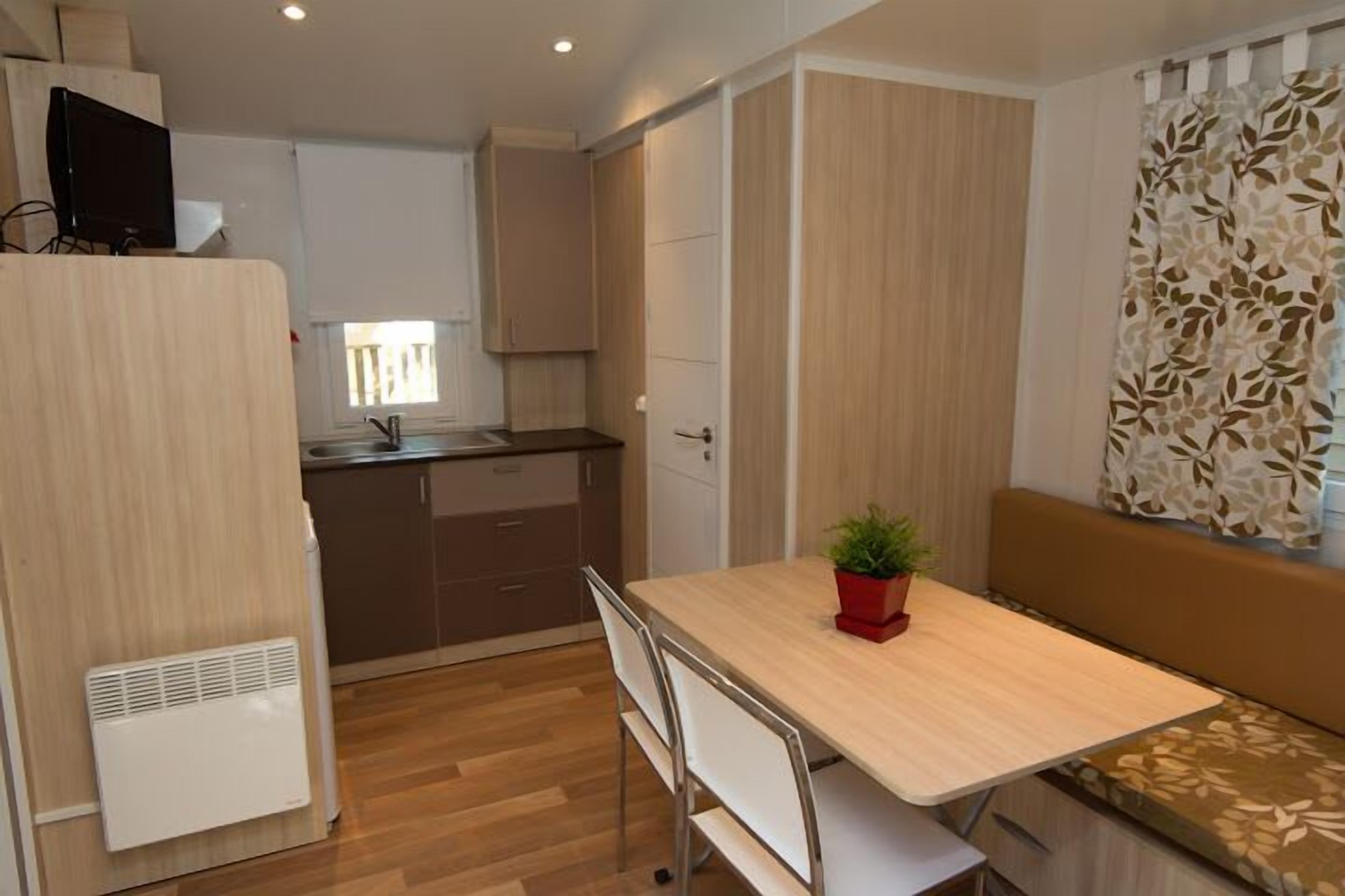 A compact kitchen with a dining area, a built-in bench, and a small potted plant.
