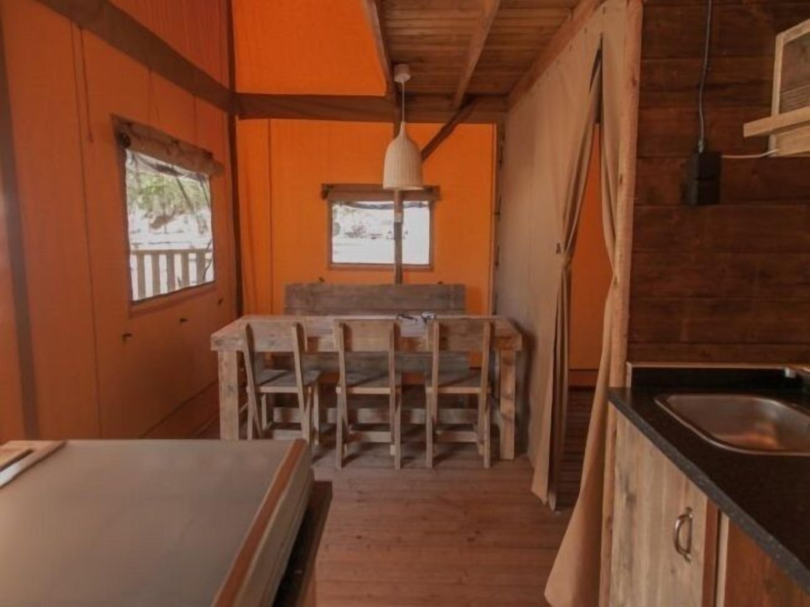 A rustic wooden interior with a dining area, a window with a view, and a kitchen counter.