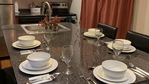 Una cocina con armarios de madera, encimera de granito y un comedor con una mesa preparada para cuatro.