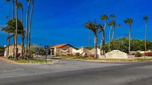 Ein Hotel mit Palmen, einem Schild und blauem Himmel.