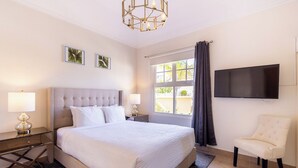 Ett hotellrum med en stor säng, en platt-TV som är monterad på väggen, en stol och konstverk på väggen.
