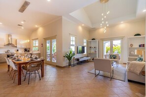 A spacious living area with a dining table, chairs, a sofa, and a TV.