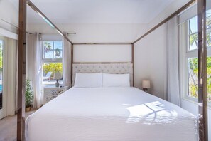 A bedroom with a large bed, a headboard, and a window with curtains.