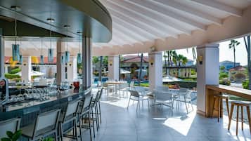 A modern outdoor bar area with a pool view, bar stools, and seating arrangements.