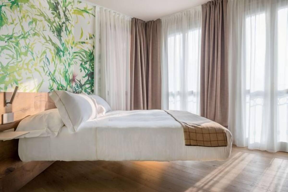 A hotel room with a bed, curtains, and a large window.
