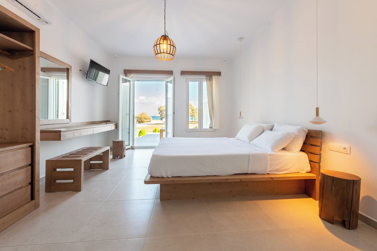 Un dormitorio con una cama grande, un banco de madera y un televisor montado en la pared.