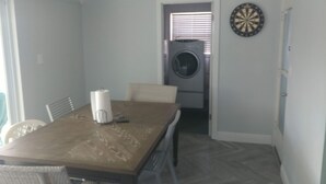 A dining area with a table, chairs, a coffee maker, and a dartboard.