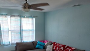 A living room with a brown sectional sofa, a white coffee table, and a ceiling fan.