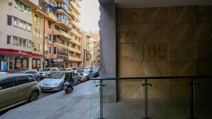 Un edificio de varios pisos con balcones, un estacionamiento con coches y el número 65 grande en una pared.