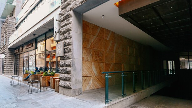 Un edificio moderno con fachada de piedra, un gran panel de madera y una entrada de vidrio.
