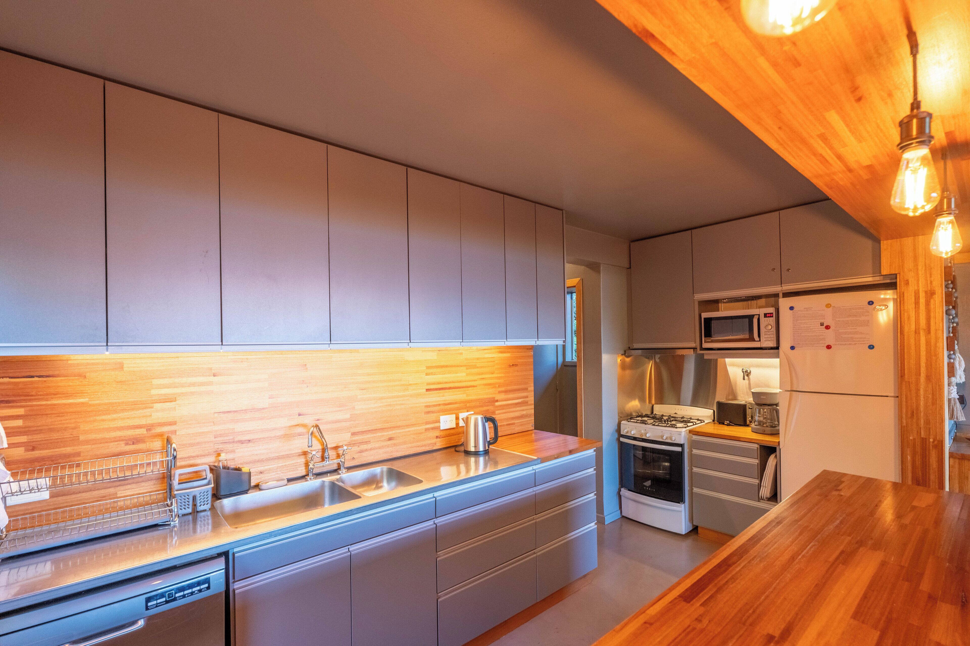 A modern kitchen with wooden cabinetry, stainless steel appliances, and a wooden countertop.