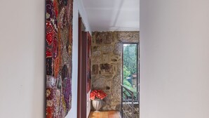A hallway with a wooden floor, a stone wall, and a large tapestry on the left. - Cottage with private pool (Briteiros São Salvador- Guimarães)