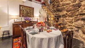 A dining area with a stone wall, a staircase, and a table set for a meal. - Cottage with private pool (Briteiros São Salvador- Guimarães)
