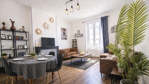 A living room with a dining table, sofa, and a large potted plant.