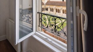 A room with a window overlooking a courtyard, a radiator, and a white door.