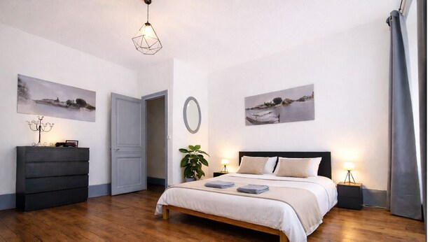 A bedroom with a bed, dresser, bedside tables, and wall art.
