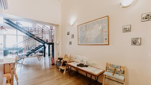 Amplia habitación con suelo de madera, una mesa de comedor, sillas, una estatua de un perro blanco y una escalera que conduce a un nivel superior.
