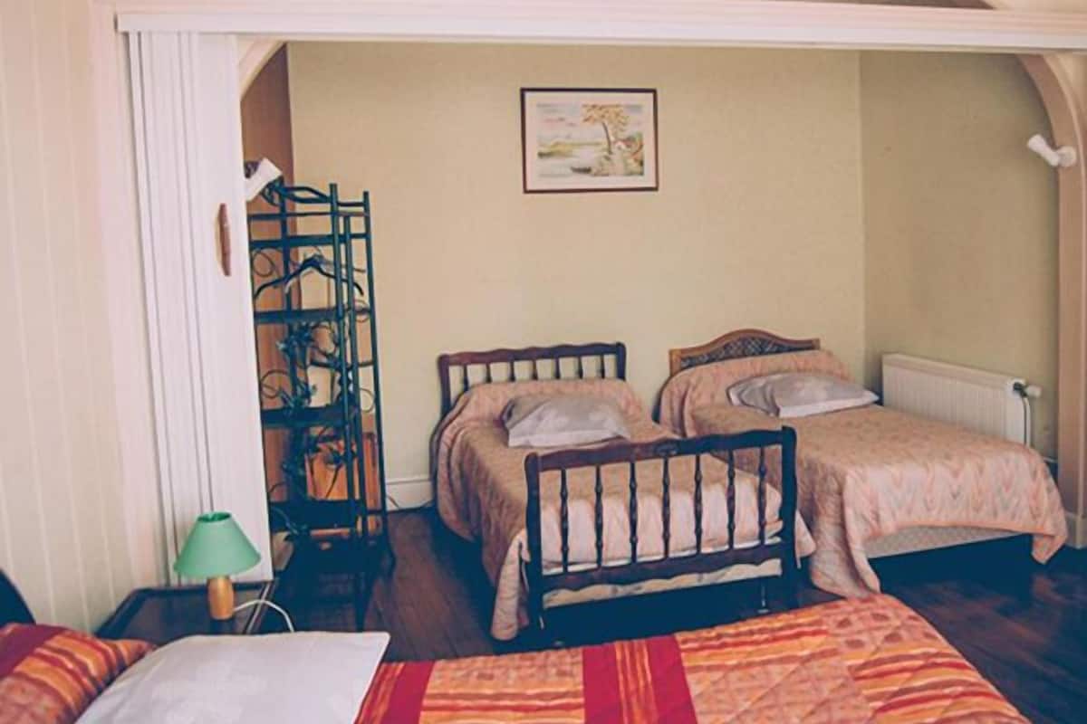 A room with two wooden beds, a radiator, a green lamp, and a framed picture on the wall.