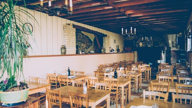 A restaurant with wooden tables and chairs, a bar area, and a potted plant. - Hotel Restaurant Maurice (Chateauroux)